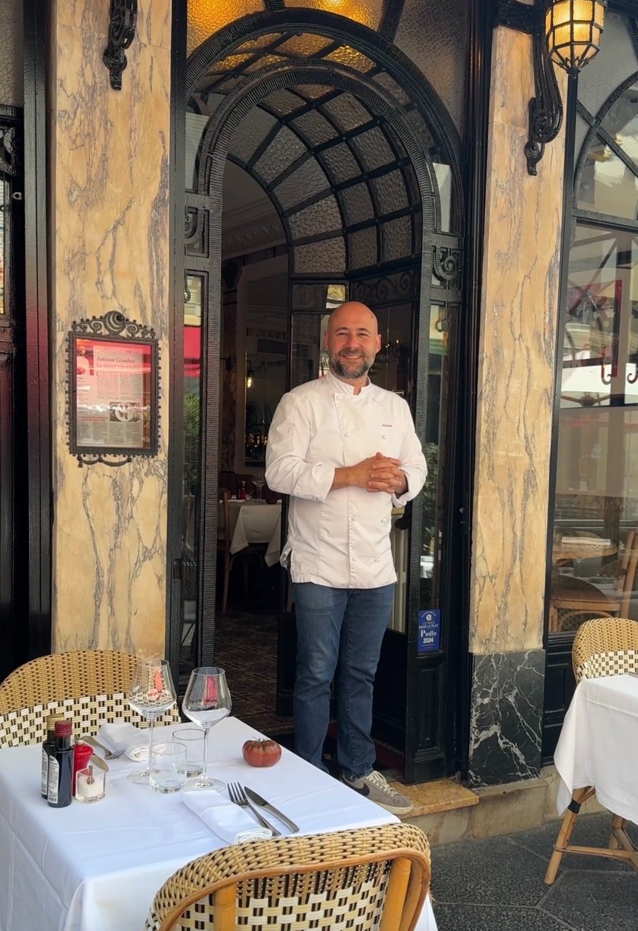 A chef holding the door open beside a table already laid